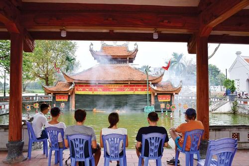 Khách nước ngoài xem trình diễn rối nước Đào Thục ở thủy đình của làng.