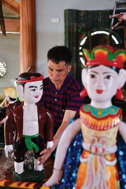 Nghệ nhân Nguyễn Đức Cường bên tượng chú tễu, một tạo hình đặc trưng trong rối nước Đào Thục.