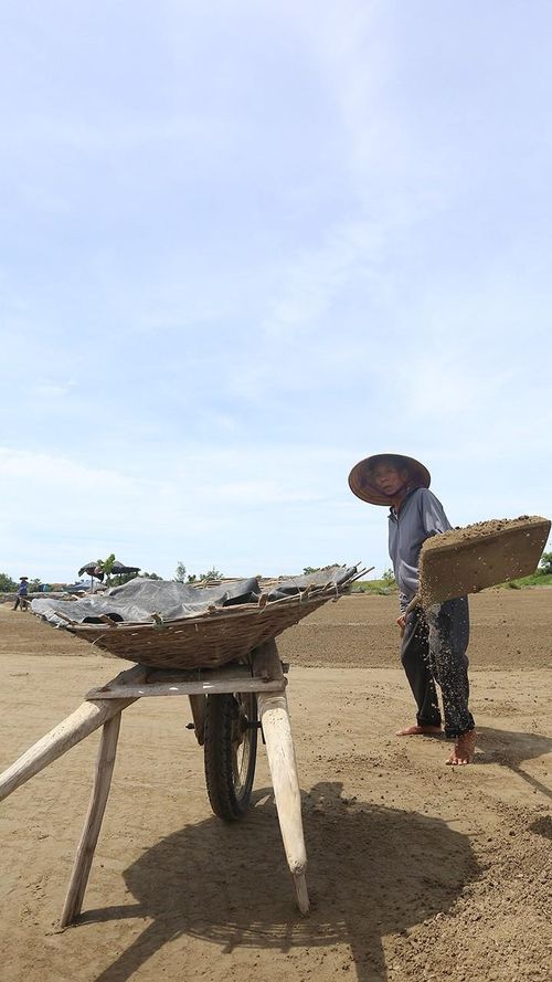 Tôi nhanh chóng cào số đất đã phơi từ sáng thành đống rồi xúc lên xe đẩy, đưa lại các bể lọc để lọc lấy nước biển.