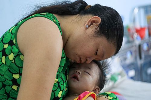  Bé Mỹ Duyên đi vào giấc ngủ trong vòng tay mẹ. Khóe miệng và cổ em vẫn còn đọng lại những vệt sữa vừa nôn ra. Những lần truyền dịch liên tục, cơn đau từ các vết loét bên trong miệng dường như quá sức với đứa trẻ 10 tháng tuổi. Ba hôm trước, bé Duyên sốt cao, nằm bệnh viện tuyến tỉnh không thuyên giảm. Chị Trần Mỹ Xuyên (40 tuổi) sốt ruột, gác lại công việc, quyết cho con lên Bệnh viện Nhi đồng 1 để chữa trị. “Bình thường con rất hay cười nhưng giờ đau quá chỉ biết khóc thôi. Mong sao con sớm khỏe”, chị Xuyên nói. 
