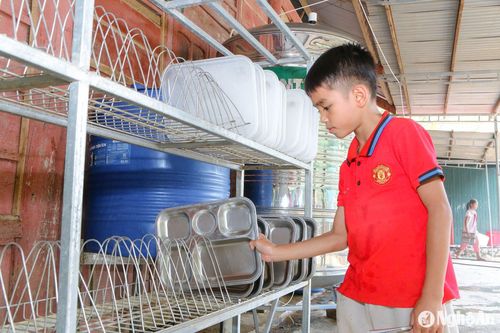 Ăn cơm xong, những đứa trẻ mang theo khay cơm của mình ra bể nước xếp hàng chờ đến lượt rửa, rửa xong cất đặt gọn gàng, ngăn nắp đúng nơi quy định. Ảnh: Đình Tuân