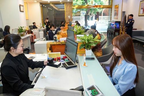  Cán bộ ngân hàng SHB hỗ trợ khách hàng áp dụng sinh trắc học. (Ảnh: Vietnam+) 