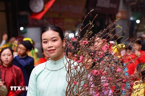 Thiếu nữ bên cành đào Xuân trong đoàn rước lễ cửa đình.(Ảnh: Thanh Tùng/TTXVN)
