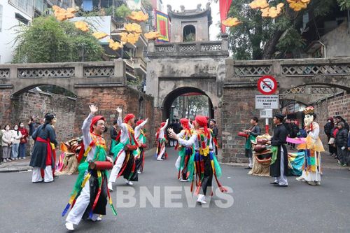 Đoàn rước lễ dừng chân trước khu vực Ô Quan Chưởng, di tích mang đậm dấu ấn kinh thành Thăng Long xưa. Các đoàn múa nghê, múa sênh tiền, múa bồng, hát xoan... biểu diễn tại điểm dừng chân tạo nên bầu không khí náo nhiệt. Ảnh: Đức Hạnh/BNEWS/TTXVN