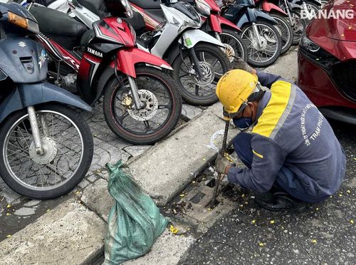 Công nhân Công ty Thoát nước và xử lý nước thải Đà Nẵng tranh thủ khơi thông cửa thu nước mưa vào chiều 11-6. Ảnh: HOÀNG HIỆP