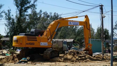 Người dân sử dụng cần cẩu để múc cát cứu tài sản bị cát vùi lấp. Ảnh: Sỹ Thắng - TTXVN