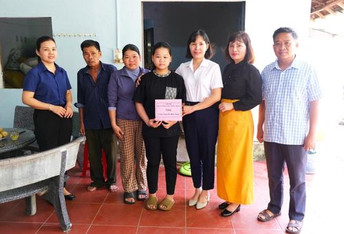 Chủ tịch Hội Nông dân thành phố Lê Thị Minh Tâm (thứ ba, bên phải sang) tặng quà em Nguyễn Thị Bảo Ngọc (xã Sơn Cẩm Hà). Ảnh: XUÂN ĐÔNG