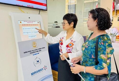 Công chức tại Điểm tiếp nhận, phục vụ hành chính công phường Kim Liên hướng dẫn người dân lấy số để thực hiện các thủ tục hành chính. (Ảnh: KHÁNH HUY)
