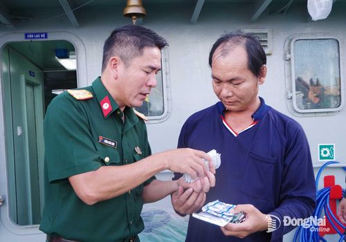 Quân y trên tàu BV98308TS cấp thuốc và hướng dẫn sử dụng cho ngư dân Võ Hoàng Rớt. Ảnh: Văn Đường