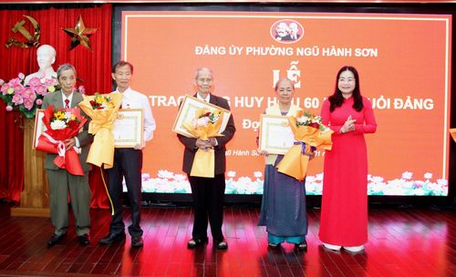 Bí thư Đảng ủy phường Ngũ Hành Sơn Mai Thị Ánh Hồng trao Huy hiệu Đảng và tặng hoa chúc mừng các đảng viên được trao Huy hiệu 60 năm tuổi Đảng. Ảnh: TRỌNG HUY
