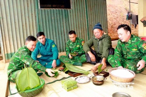 Ông Xồng Xìa Lỳ (đội mũ) - người uy tín bản Huồi Mới gói bánh chưng cùng cán bộ tổ công tác biên phòng Huồi Mới. Ảnh: K.L