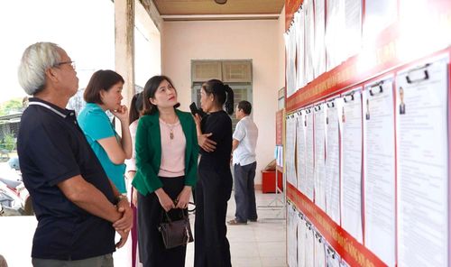 Cử tri thôn Phước Viên (xã Nông Sơn) theo dõi tiểu sử người ứng cử niêm yết tại khu vực bỏ phiếu. Ảnh: MINH THÔNG