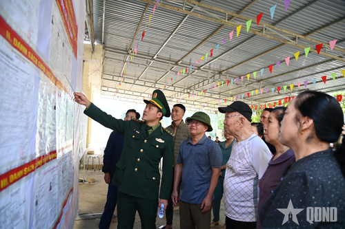 Cán bộ Đồn Biên phòng cửa khẩu Ma Lù Thàng hướng dẫn nhân dân bản Pa Nậm Cúm, xã Phong Thổ, tìm hiểu thông tin về đại biểu tham gia ứng cử.