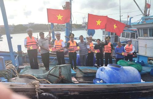 Bộ đội Biên phòng và Hải quân tặng cờ Tổ quốc cho ngư dân đang neo tàu tại đảo Trường Sa Lớn. Ảnh: BPKH.