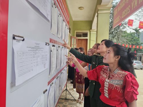  Cử tri ở bản Phồng tìm hiểu thông tin về người ứng cử trước lúc bỏ phiếu 