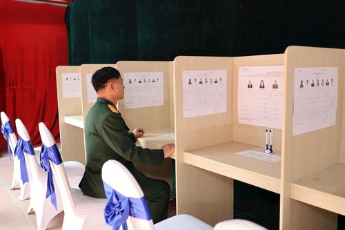 Thành viên đoàn kiểm tra nội dung dán niêm yết tại ca bin khu vực bỏ phiếu. Ảnh: Hoa Thành