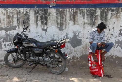  Một người đàn ông ngồi trên bình gas rỗng, chờ bên ngoài một đại lý gas tại Noida, Ấn Độ, ngày 11/3. Ảnh: Reuters. 