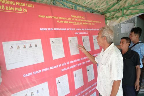 Ngư dân Võ Tiền (áo trắng) đang tìm hiểu tiểu sử, quá trình công tác của từng ứng cử viên