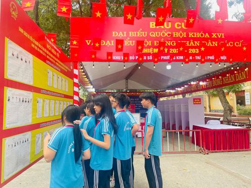 Các bạn trẻ đang theo học tại trường THCS Đống Đa theo dõi thông tin bầu cử tại điểm bầu cử số 21 địa bàn phường Kim Kiên