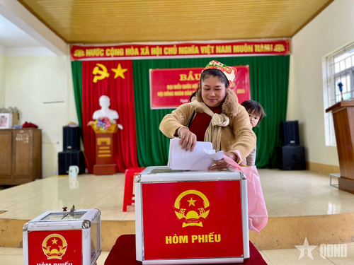 Một người mẹ địu con cùng đi bầu cử.