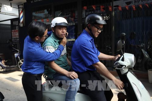 Đoàn viên thanh niên Phường Bình Thạnh, Tp Hồ Chí Minh đến nơi cư trú hỗ trợ cử tri khiếm thị di chuyển đến điểm bỏ phiếu bầu cử. Ảnh: Xuân Anh -TTXVN 