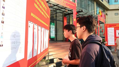 Các cử tri nghiên cứu danh sách ứng cử viên trước khi tham gia bỏ phiếu