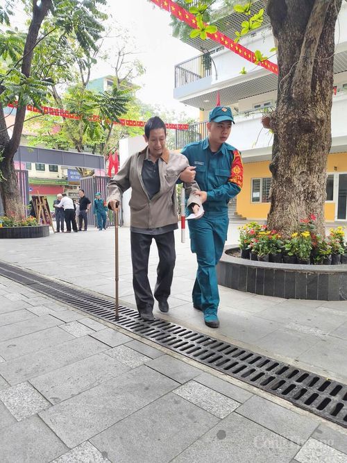 Cử tri có sức khỏe yếu được hỗ trợ đưa vào khu vực nhận phiếu. Ảnh: Nguyễn Hòa