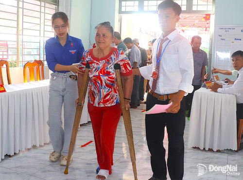 Một phụ nữ bị thương ở chân nhưng sẵn sàng tham gia thực hiện quyền và nghĩa vụ công dân của mình. Ảnh: An Nhơn