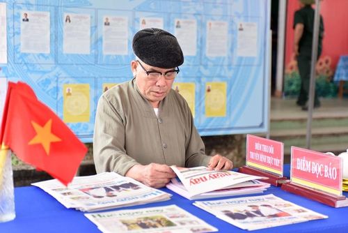  Cử tri phường Hương An tranh thủ đọc Báo Huế ngày nay khi đến bỏ phiếu. Ảnh: Đức Quang
