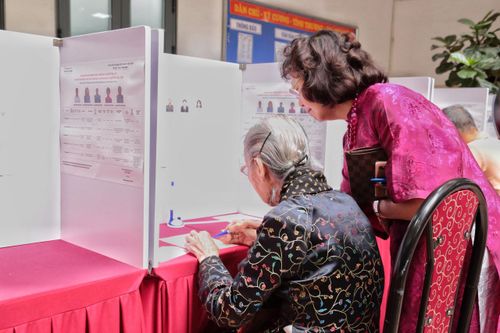  Sau khi được hướng dẫn các bước cần thiết, cụ Thuận cẩn thận nhận lá phiếu và thực hiện các thao tác theo quy định cùng với sự hỗ trợ của con gái. Dù tuổi cao, cụ vẫn giữ sự tập trung và cẩn trọng trong từng bước. 