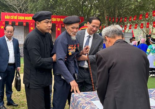 Ông Hoàng Trung Nhất (86 tuổi), cử tri cao tuổi nhất xã Tân Trào, được lực lượng chức năng dìu đến điểm bỏ phiếu