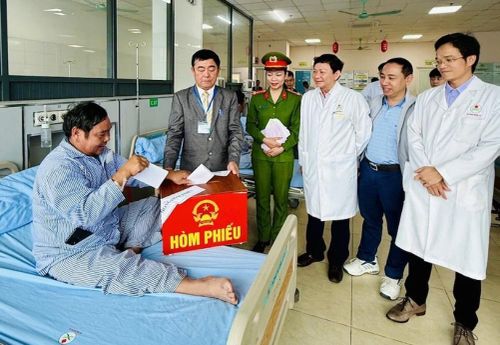Thành viên Tổ bầu cử mang hòm phiếu phụ đến tận giường bệnh để cử tri đang điều trị bệnh thực hiện quyền công dân. Ảnh: Đình Hợp