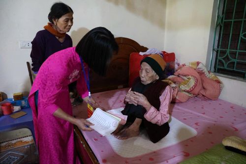 Cán bộ xã Minh Châu hướng dẫn cụ Nguyễn Thị Tính trực tiếp tham gia bỏ phiếu. Ảnh: Sơn Tùng