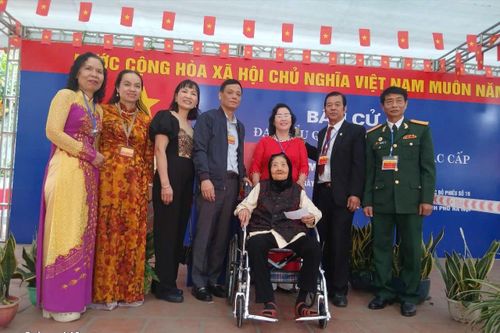 Cụ Trịnh Thị Bê, 101 tuổi trực tiếp đến bỏ phiếu ở khu vực bỏ phiếu số 19, đơn vị bầu cử số 5 trong vòng tay ấm áp của gia đình và những người làm công tác bầu cử. Ảnh: PV