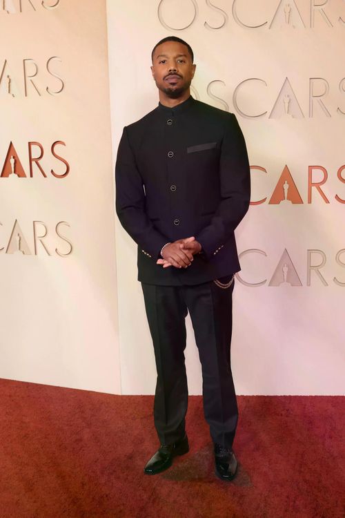 Michael B. Jordan diện suit đen của Louis Vuitton với thiết kế cổ đứng hiện đại. Trang phục có phom dáng gọn gàng, kết hợp các chi tiết kim loại nhỏ tạo điểm nhấn.