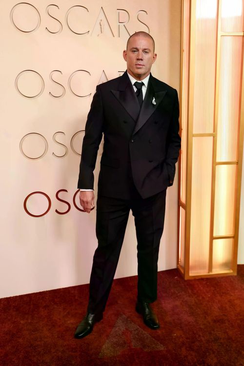 Channing Tatum diện suit đen hai hàng khuy của Versace. Nam diễn viên phối cùng áo sơ mi trắng và cà vạt đen, giữ phong cách cổ điển, nam tính.