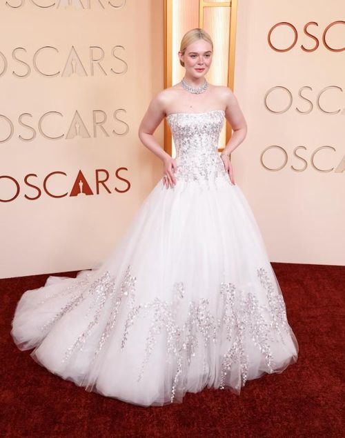 Elle Fanning tỏa sáng trong váy dạ hội trắng cúp ngực dáng công chúa, thân váy đính họa tiết ánh kim tinh xảo và chân váy tulle bồng bềnh. Cô hoàn thiện vẻ ngoài lãng mạn với trang sức đặt may riêng của Givenchy cùng các món trang sức cổ điển. Ảnh: Harpers Bazaar