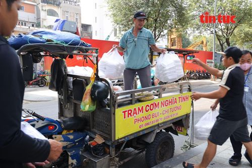 Khoảng 9 giờ 45 phút, xe chở cơm dừng lại trước điểm phát. Mọi người nhanh chóng cùng nhau phụ chuyển các thùng cơm xuống để chuẩn bị phát cho người bệnh.