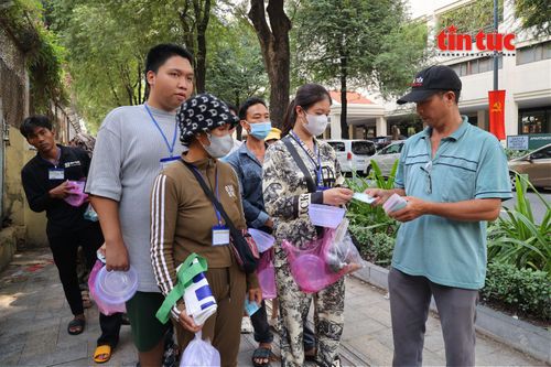 Đúng 10 giờ sáng, mọi người xếp thành hai hàng ngay ngắn, nhận thẻ rồi lần lượt vào lấy cơm.