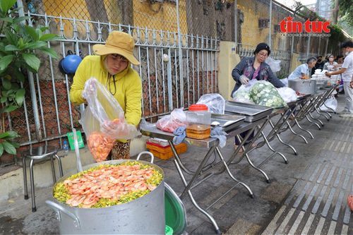 Chị Tưởng (áo vàng) cùng các thành viên trong nhóm nhanh chóng bày các phần cơm ra bàn, chuẩn bị cho buổi phát cơm.