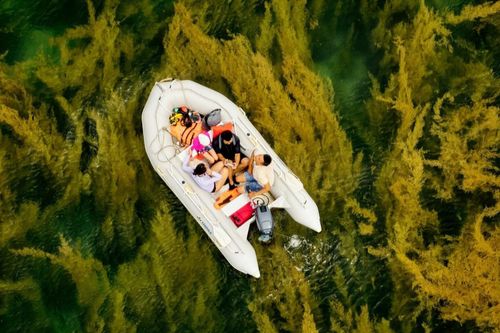 Hiếu Linh (áo đen) ngồi trên ca nô, sử dụng drone để tác nghiệp tại vịnh Đầm Tre, Côn Đảo, tháng 5/2025.
