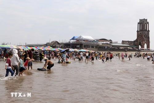 Đông đảo người dân và khách du lịch đến tắm biển tại khu vực nhà thờ đổ Hải Lý. (Ảnh: Công Luật/TTXVN)