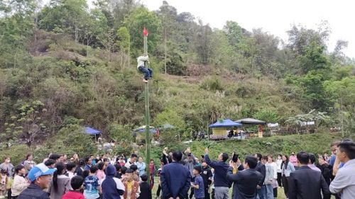 Trò chơi trèo cột mỡ tại lễ hội thu hút người dân tham gia và cổ vũ.
