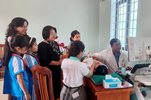 Lãnh đạo Hội Bảo trợ bệnh nhân nghèo tỉnh thăm hỏi, động viên các em học sinh đang được khám sàng lọc - Ảnh: T.L