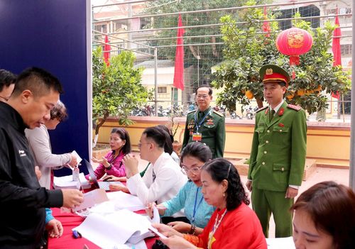 Thành viên tổ bầu cử bỏ phiếu hướng dẫn, giải đáp thắc mắc cho cử tri. Ảnh: PV