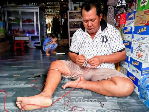 Anh Kim Văn Hậu cặm cụi nối lại mấy sợi dây bóng đèn điện chạy bằng bình ắc quy.