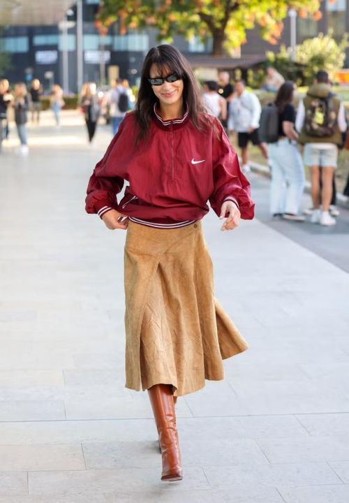 Heritage sportswear trở lại mạnh mẽ nhờ các nhà mốt như Miu Miu, Lacoste, Area hay Issey Miyake. Bella Hadid là minh chứng điển hình: cô phối jacket thể thao màu sắc nổi bật với chân váy da lộn và bốt da cao gối màu nâu, tạo sự cân bằng thú vị giữa nét sporty và chất liệu giàu kết cấu, nâng cấp bộ đồ thể thao truyền thống thành statement look mùa xuân. Ảnh: Getty Images