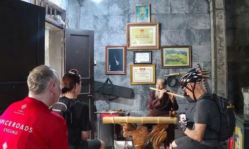Du khách quốc tế đến thăm đền Thái Vi thích thú ghi lại hình ảnh cụ Thim biểu diễn âm nhạc dân tộc, sử dụng nhiều loại nhạc cụ truyền thống. Ảnh: Đình Minh