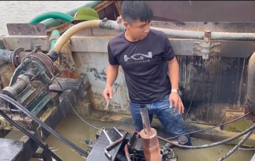 Đại úy Nguyễn Xuân Hải sửa chữa máy ghe của "cát tặc" đã bị bắt giữ để đưa về nơi xử lý.
