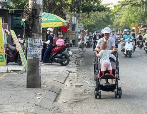 Một người đàn ông vất vả đẩy xe nôi dưới lòng đường Nguyễn Huy Tưởng trong sáng 24-3